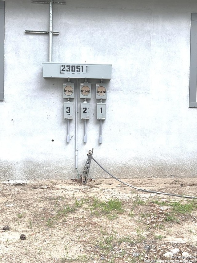 details featuring electric meter and stucco siding