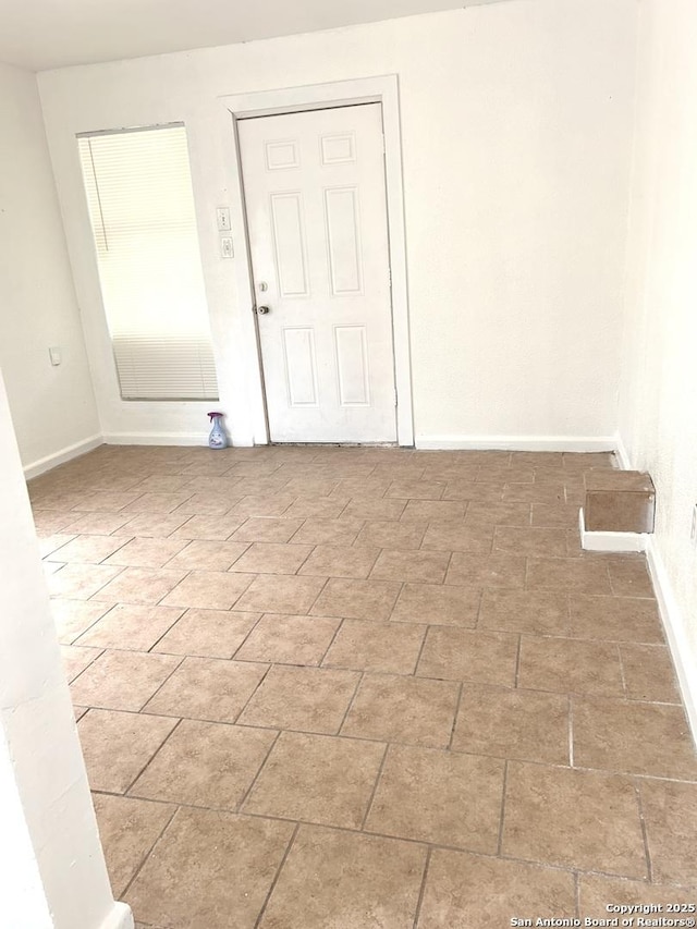 empty room featuring baseboards and brick floor
