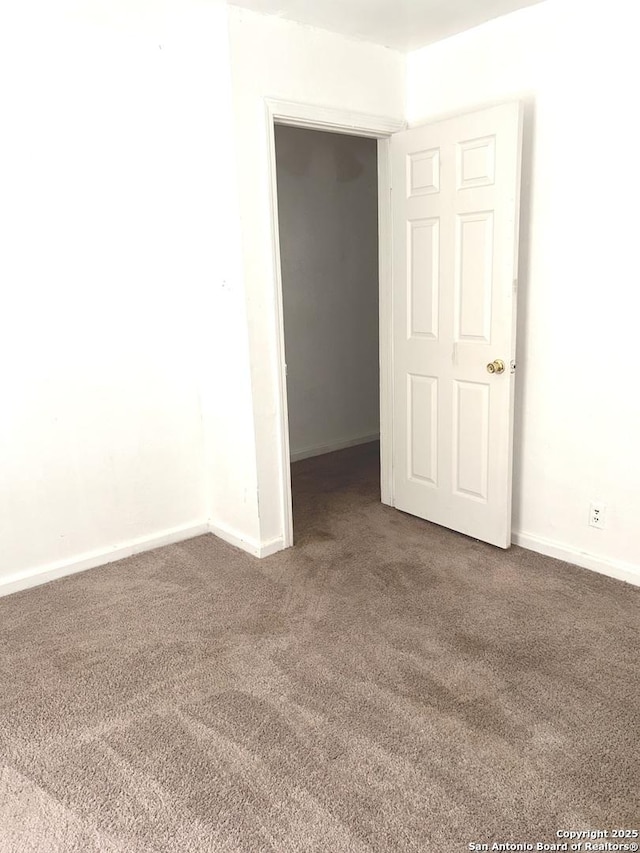 carpeted empty room featuring baseboards