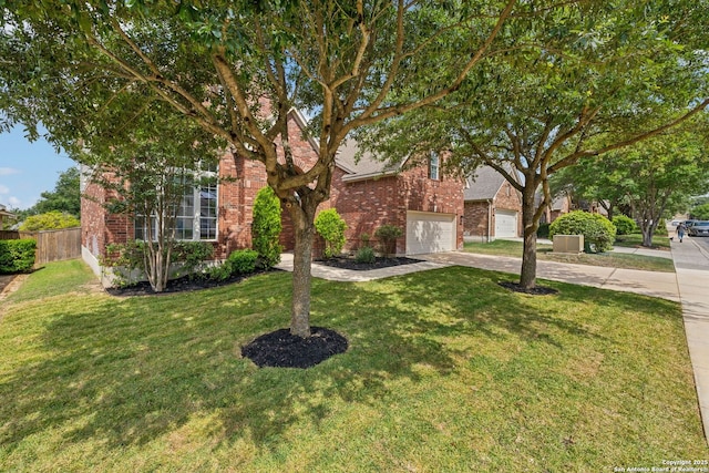 view of property hidden behind natural elements featuring brick siding, driveway, fence, and a front yard