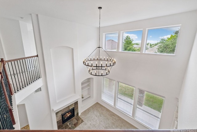 room details featuring visible vents, built in shelves, a tile fireplace, a chandelier, and carpet