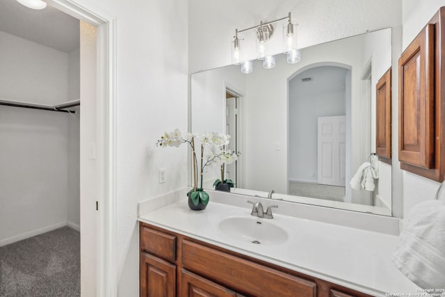 bathroom with vanity, a walk in closet, and visible vents