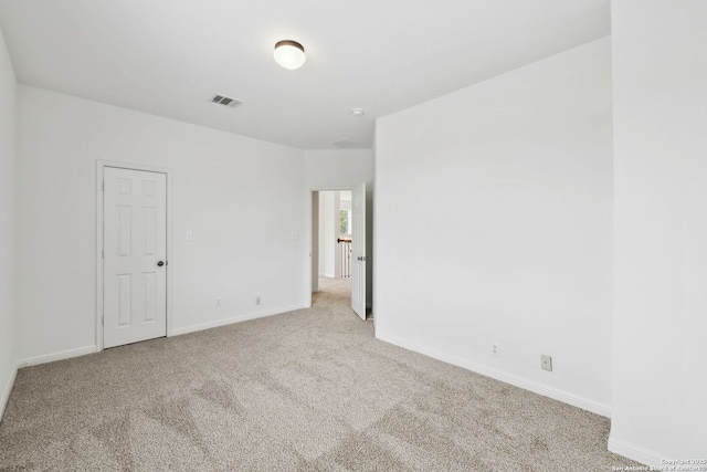 carpeted spare room with visible vents and baseboards