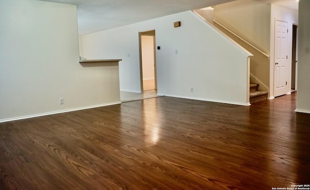 unfurnished living room with baseboards, stairs, and wood finished floors