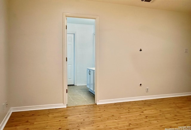 empty room featuring baseboards, light wood-style flooring, and visible vents