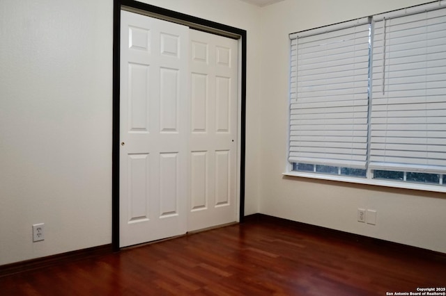 unfurnished bedroom featuring dark wood-type flooring and a closet