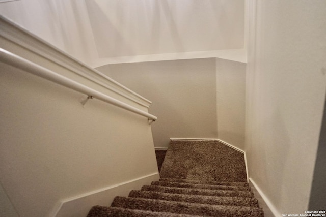staircase featuring carpet flooring and baseboards