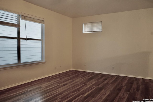 spare room featuring dark wood-type flooring and baseboards