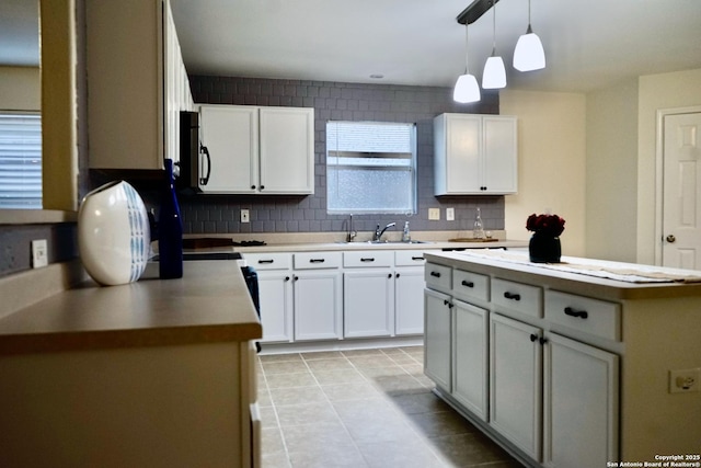 kitchen with a sink, decorative backsplash, stainless steel microwave, and white cabinets