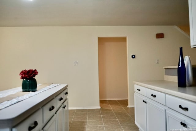 kitchen with light countertops, white cabinetry, baseboards, and light tile patterned flooring