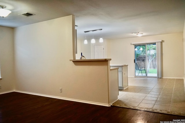 empty room featuring baseboards, wood finished floors, and visible vents