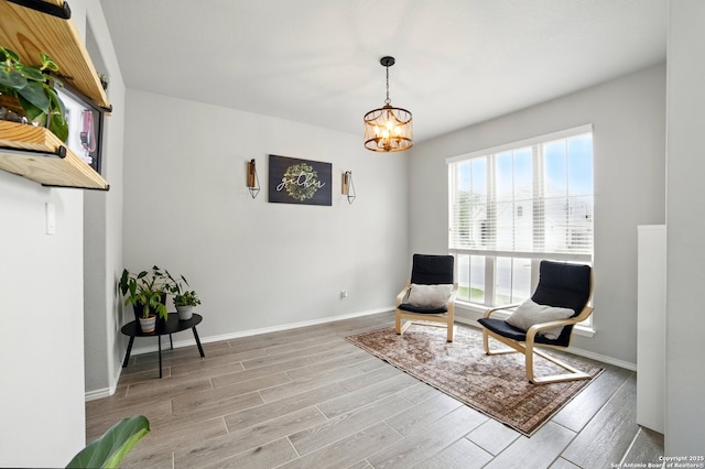 living area featuring baseboards, a chandelier, and light wood-type flooring