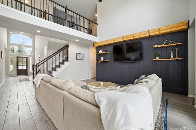 living area with wood finished floors, baseboards, an inviting chandelier, a high ceiling, and stairs