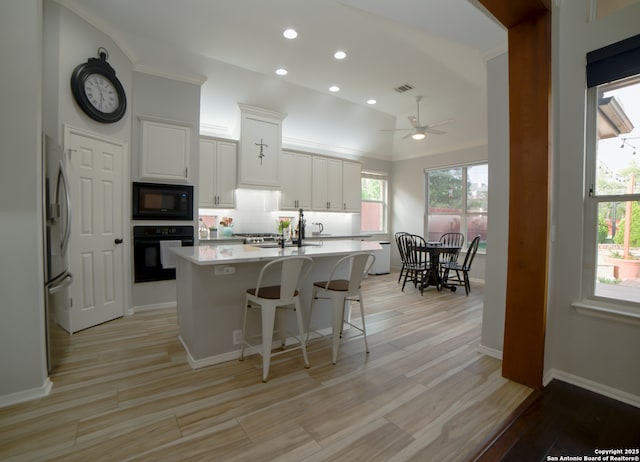 kitchen featuring ceiling fan, a kitchen island with sink, white cabinets, black appliances, and recessed lighting