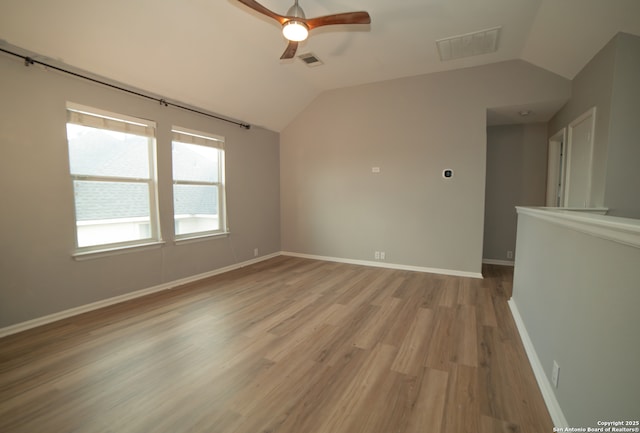 unfurnished room with ceiling fan, visible vents, vaulted ceiling, and light wood-type flooring