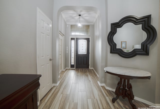 foyer entrance with light wood-type flooring, ornamental molding, and baseboards