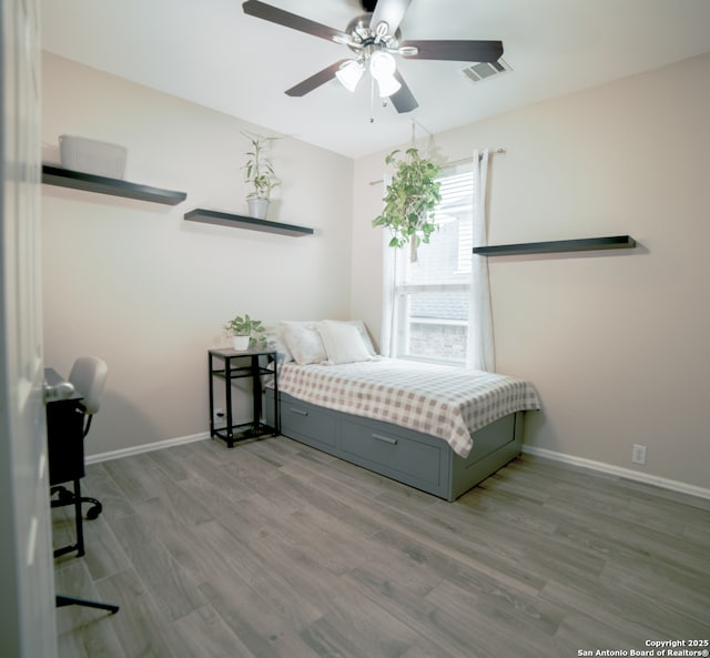 bedroom with baseboards, ceiling fan, wood finished floors, and visible vents