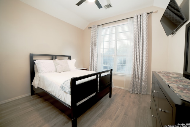 bedroom with visible vents, baseboards, wood finished floors, and vaulted ceiling
