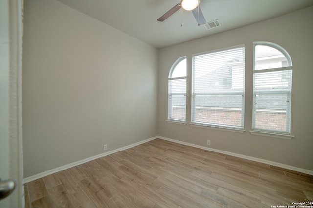 spare room featuring visible vents, a ceiling fan, light wood-style floors, and baseboards