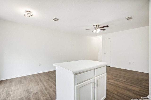 spare room featuring a ceiling fan, baseboards, visible vents, and wood finished floors