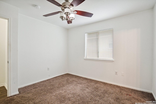empty room featuring dark colored carpet, baseboards, and ceiling fan