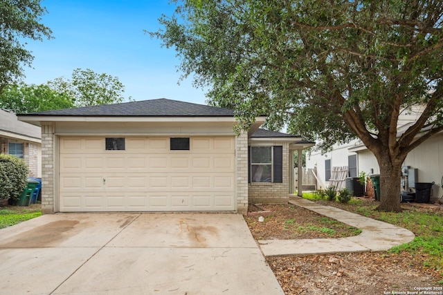 view of front facade with a shingled roof and concrete driveway