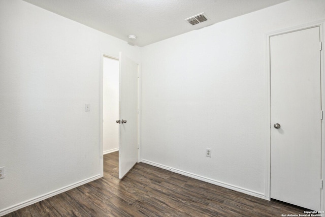 spare room featuring visible vents, dark wood finished floors, and baseboards