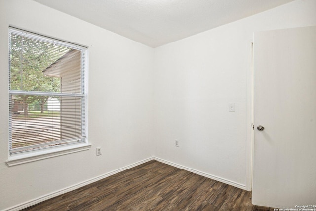 spare room featuring baseboards and dark wood finished floors