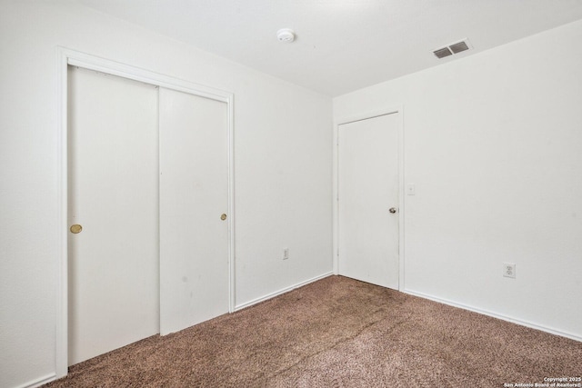 unfurnished bedroom with visible vents, carpet, and a closet