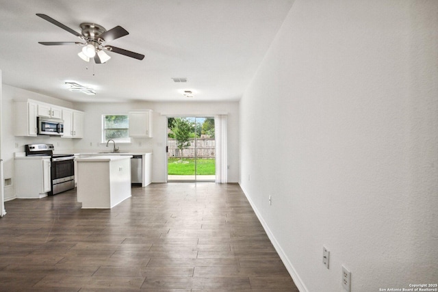 kitchen featuring ceiling fan, a kitchen island, visible vents, appliances with stainless steel finishes, and baseboards