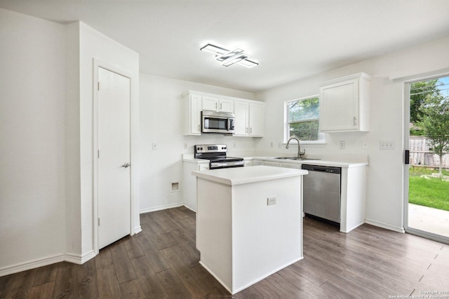 kitchen featuring dark wood-style flooring, a sink, stainless steel appliances, white cabinetry, and a kitchen island