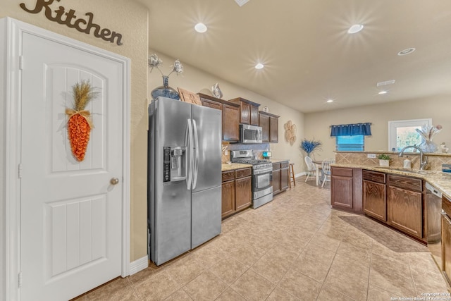 kitchen with light stone countertops, a sink, stainless steel appliances, baseboards, and recessed lighting