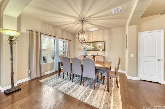 dining room with a chandelier, baseboards, visible vents, and wood finished floors