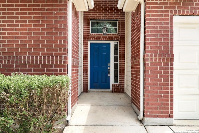 entrance to property with an attached garage and brick siding