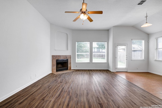 unfurnished living room with a ceiling fan, visible vents, dark wood finished floors, and a fireplace