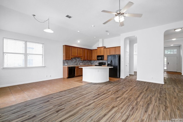 kitchen with visible vents, arched walkways, black appliances, lofted ceiling, and open floor plan
