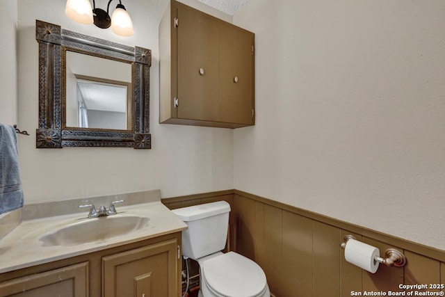 bathroom with vanity, wainscoting, and toilet