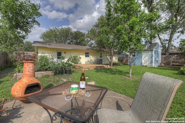 view of patio / terrace with a storage shed, fence, and an outbuilding