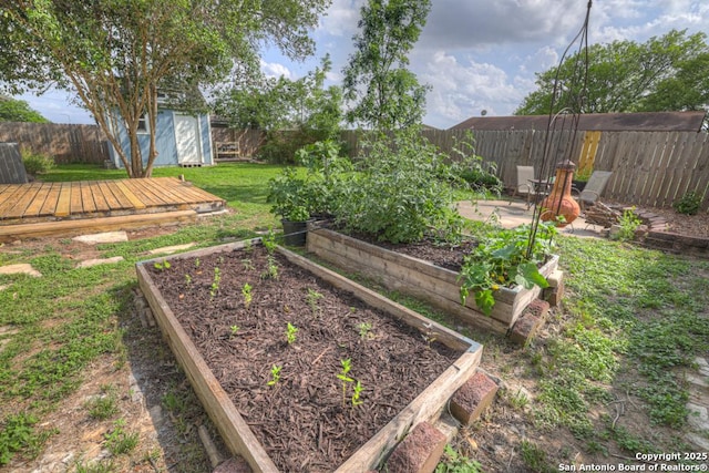 view of yard featuring a storage unit, a fenced backyard, and a vegetable garden