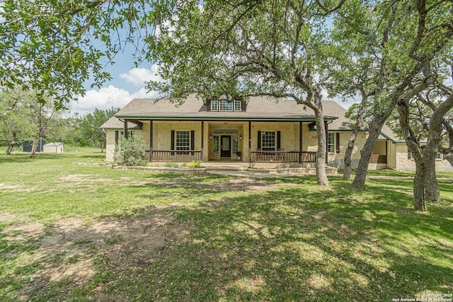 back of property with covered porch, an outbuilding, a shed, a yard, and a shingled roof