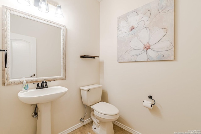 bathroom featuring baseboards, tile patterned flooring, and toilet