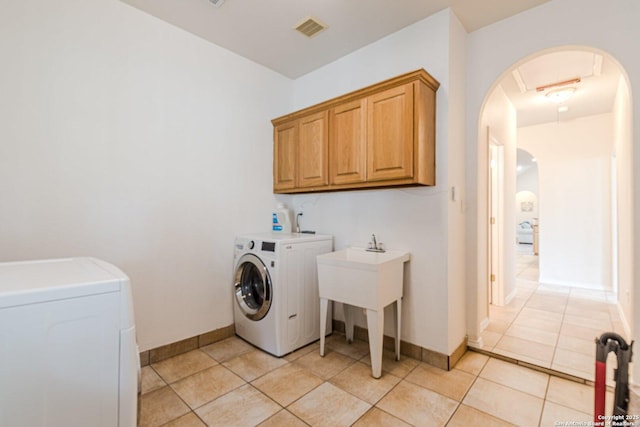 washroom featuring cabinet space, arched walkways, visible vents, and washing machine and dryer