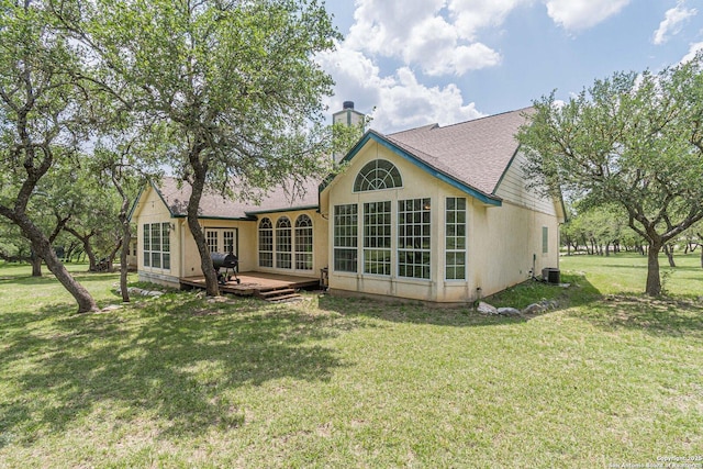 rear view of house featuring a shingled roof, stucco siding, a deck, a chimney, and a lawn