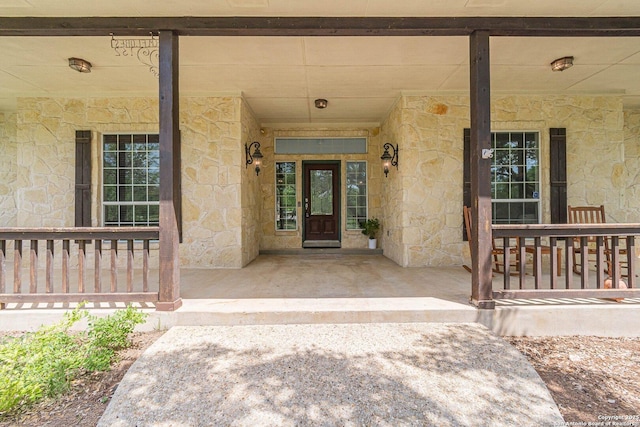 doorway to property with covered porch and stone siding