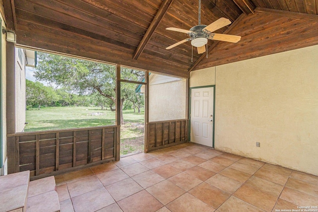 unfurnished sunroom with a ceiling fan and beamed ceiling