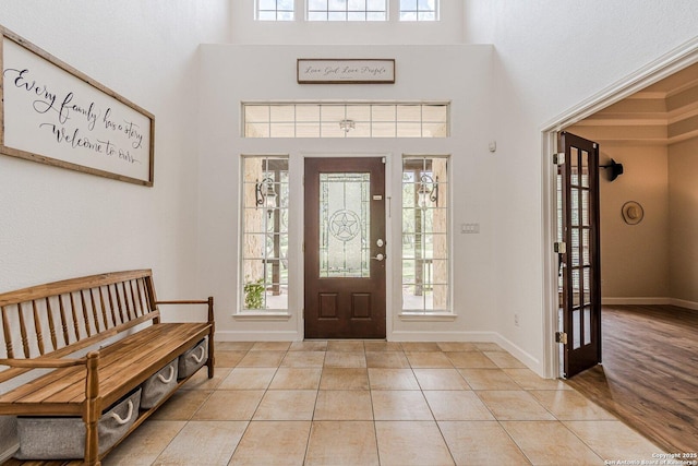 entrance foyer featuring baseboards, light tile patterned floors, and a towering ceiling