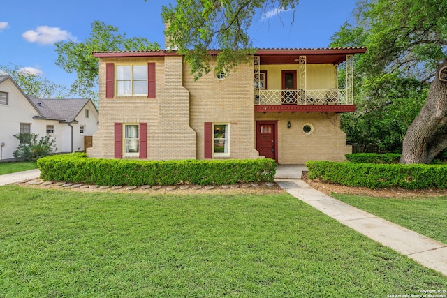view of front of home with brick siding, a balcony, and a front lawn