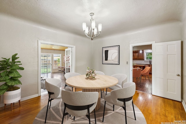 dining area featuring light wood-style floors, baseboards, and a notable chandelier