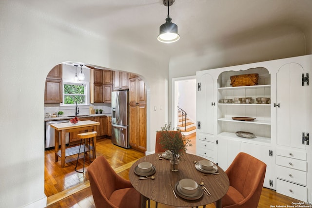dining area featuring stairs, arched walkways, and wood finished floors