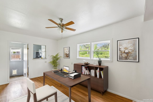 office space with baseboards, ceiling fan, and light wood-style flooring